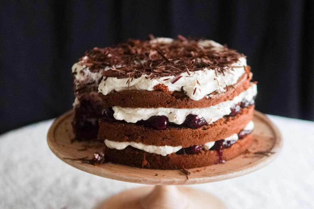Closeup of layered Black Forest cake with cherries peeking through and chocolate shavings on top.