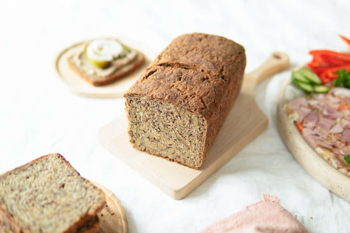 German whole grain bread with seeds sliced open and sitting on a wooden cutting board.