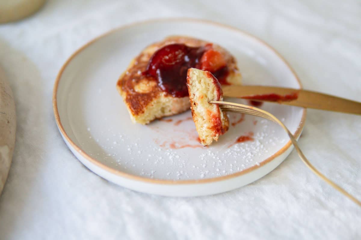 A bite of German yeast pancakes with plum compote.