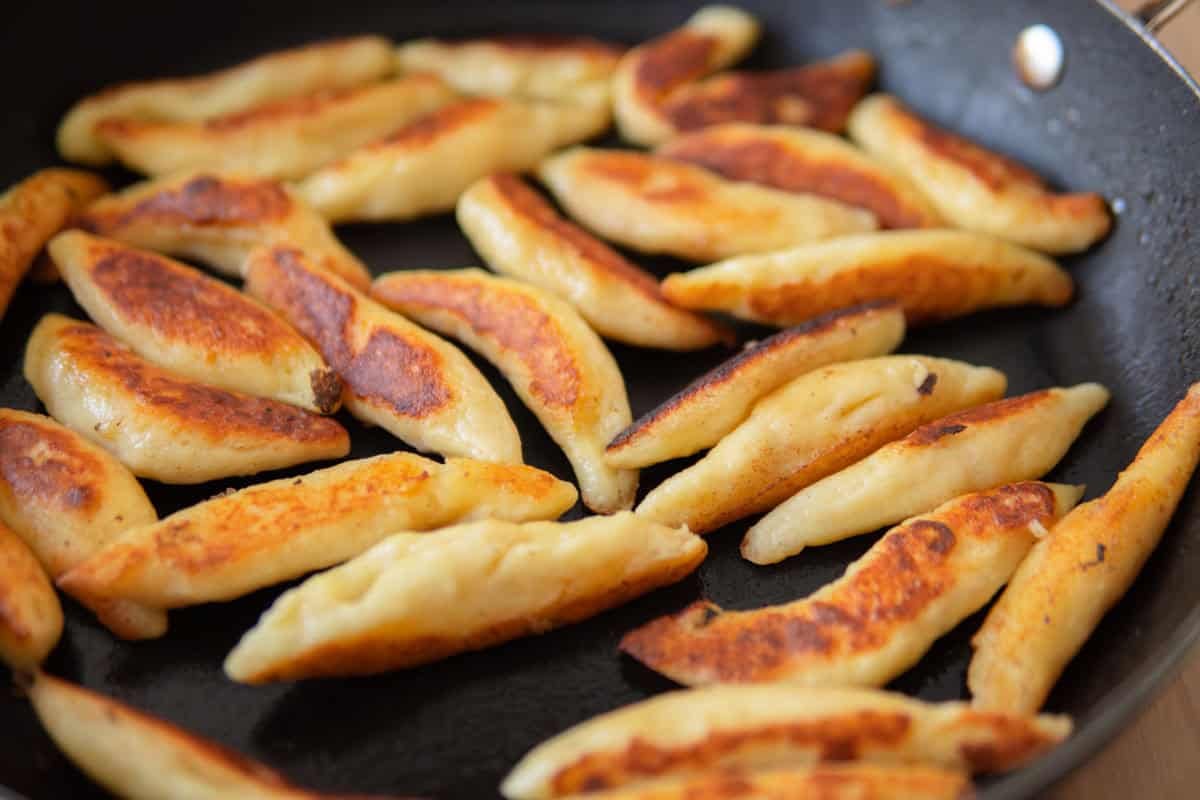 Zooming into a pan full of golden-crispy fried Schupfnudeln.